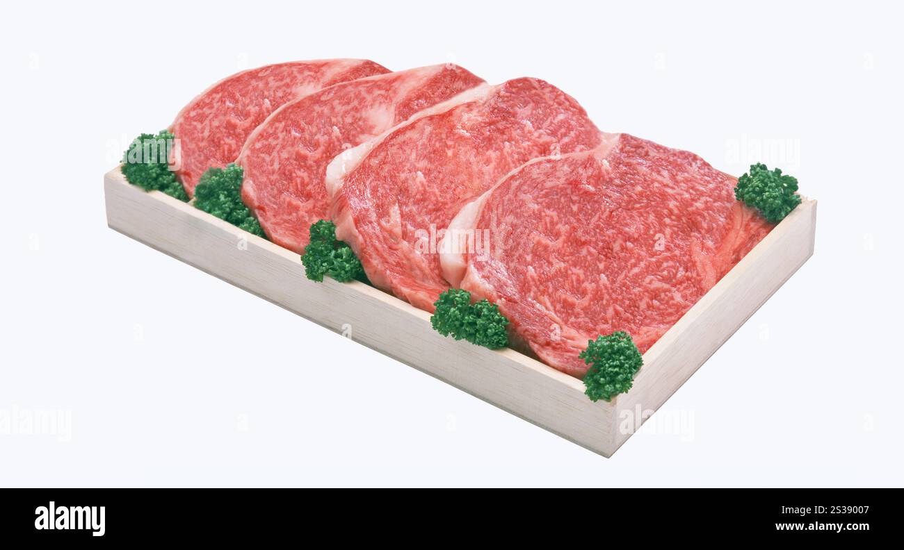 Vier erstklassige Rohbeef-Steaks auf einem hölzernen Schneidebrett, isoliert auf weißem Hintergrund. Frisches rohes Rindfleisch auf Holzbrett Stockfoto