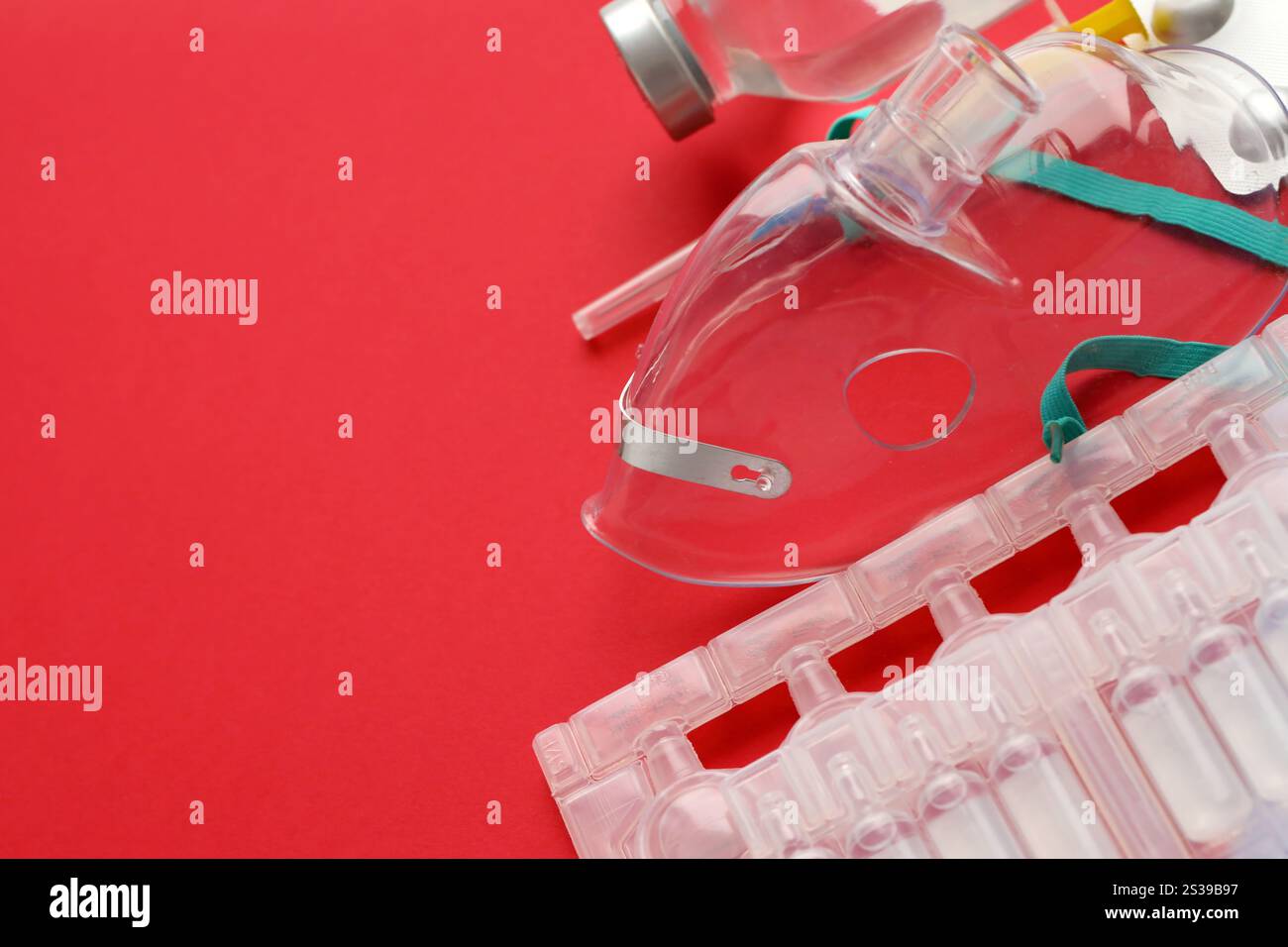Coronavirus-Behandlungskonzept. Eine medizinische Gesichtsmaske Vernebler für die Behandlung der Atemwege und Packs von Ampullen flach auf rotem Hintergrund gelegt. Stockfoto