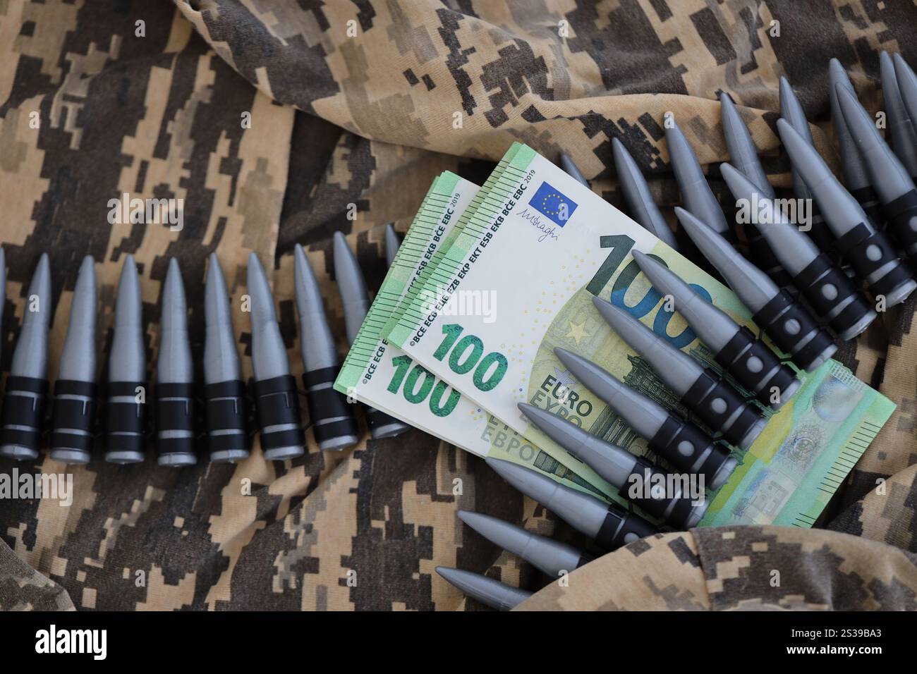 Bündel Euroscheine und ein Maschinengewehrgürtel auf der Tarnuniform eines ukrainischen Soldaten. Konzept der Kriegsfinanzierung, Bestechung oder Spende. Hilfe zu Stockfoto