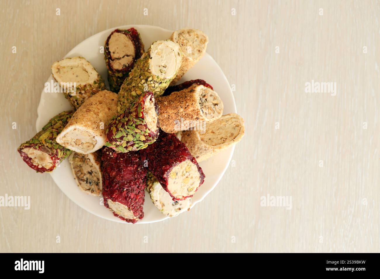 Viele Rollen türkischer Delikatesse mit verschiedenen Aromen und Füllungen auf weißem Teller auf dem Tisch. Teile von türkischen Lokumu-Süßigkeiten. Viele Rollen türkischer Delikatessen Stockfoto