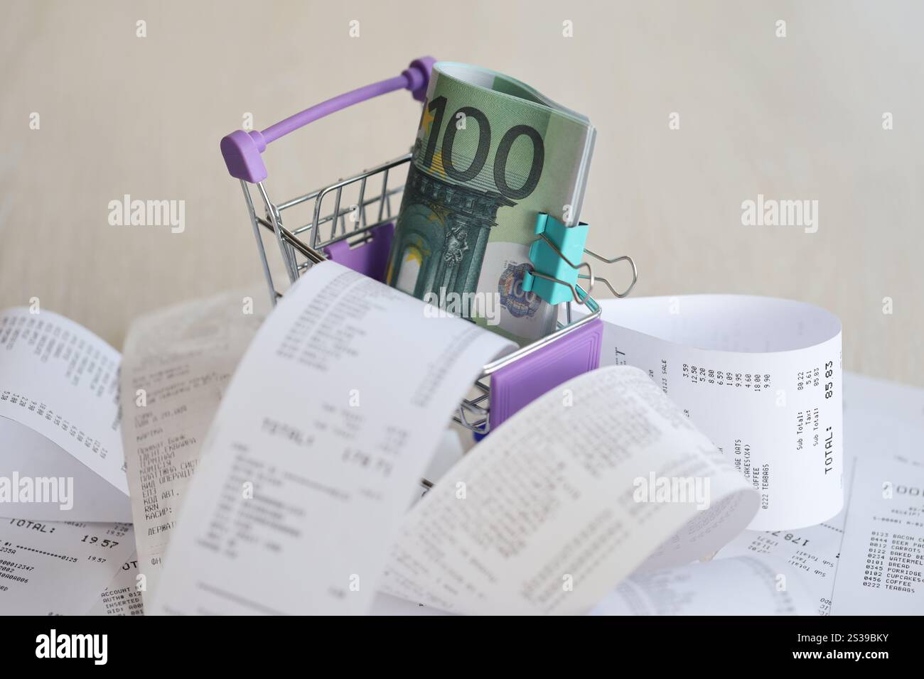Euro-Scheine in Einkaufswagen, umgeben von vielen Papierquittungen aus der Nähe. Euro-Scheine in Einkaufswagen, umgeben von vielen Papieren Stockfoto