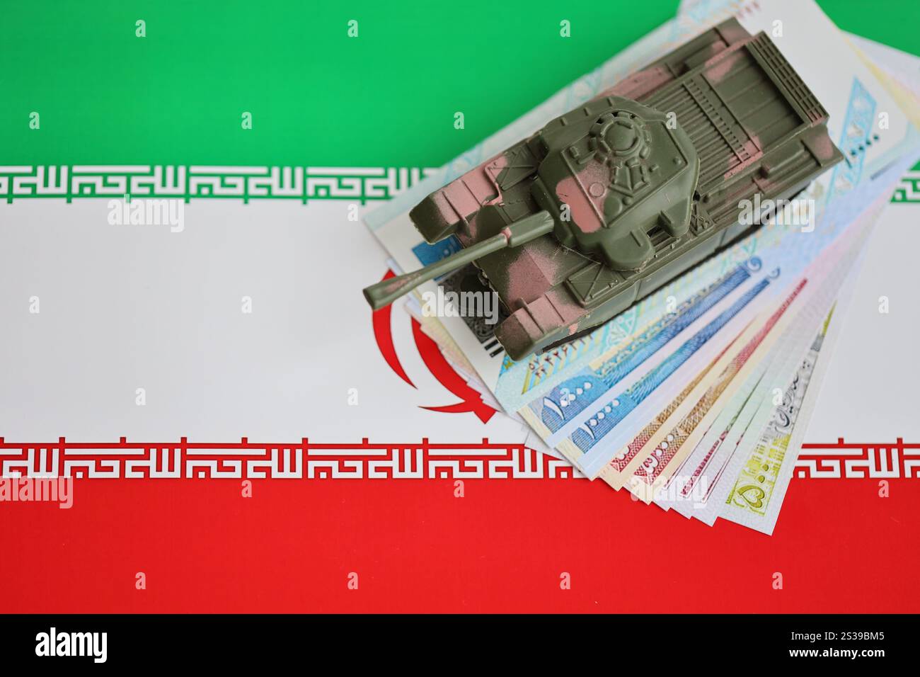 Iranische Armee Spielzeugpanzer-Antrieb auf iranischen Rial-Wechseln auf der Flagge der Islamischen Republik Iran Nahaufnahme. Iranische Armee-Spielzeugpanzer-Antrieb auf iranische Stockfoto