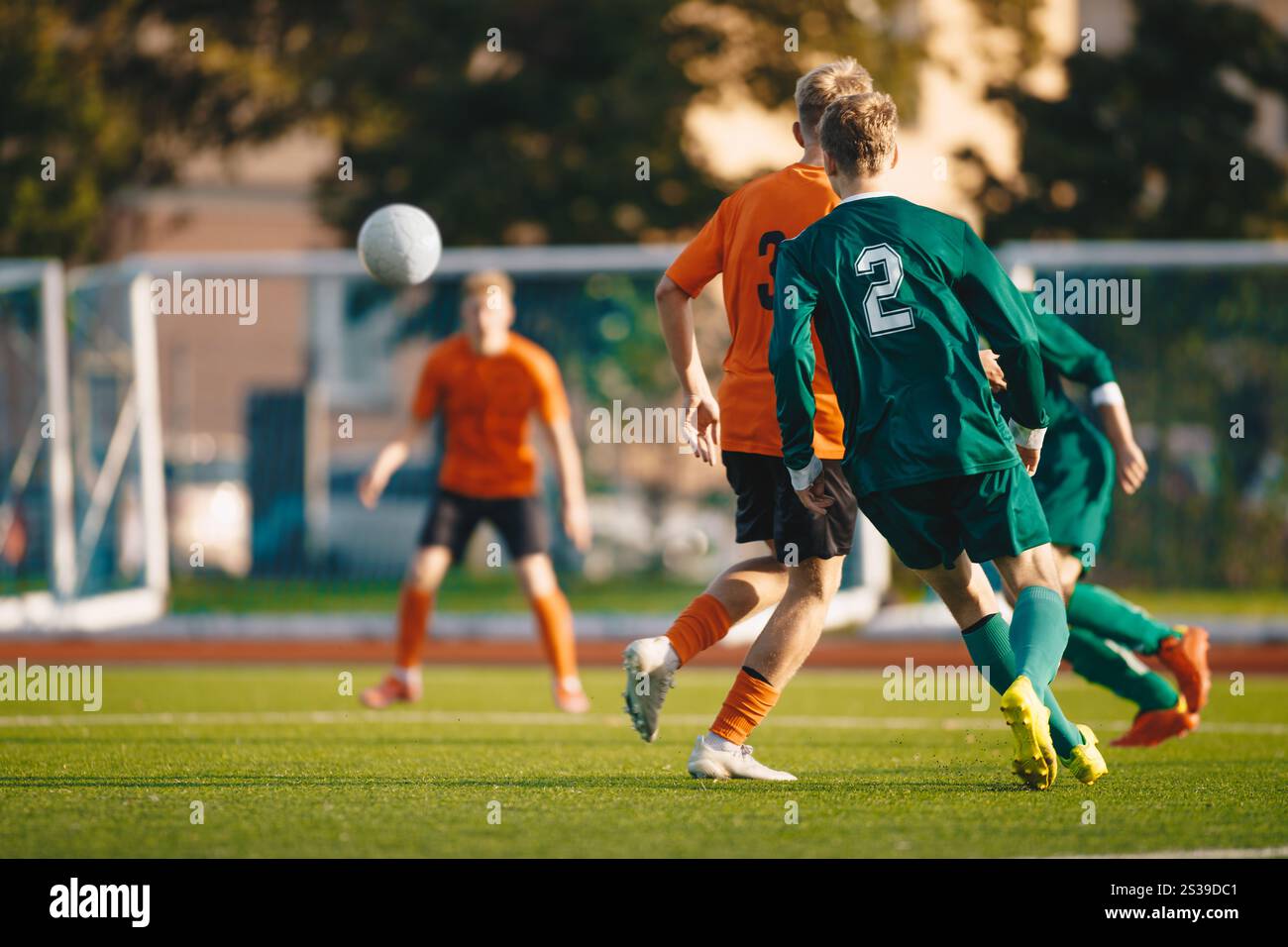 Fußballspieler kicken während eines Spiels im Fußballstadion einen Ball auf ein Tor zu. Jugendfußballmannschaften in einem Spiel. Fußballer in Aktion auf dem Stockfoto