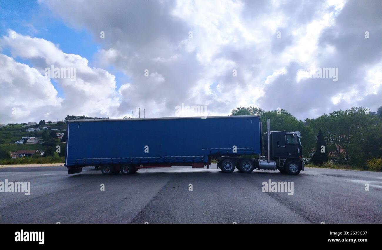 Ein schwarzer Retro-Sattelzug parkt am Straßenrand, ohne dass jemand in der Nähe ist. Das Fahrzeug steht mit eingeschalteten Warnblinkleuchten gegen einen Stockfoto Ein schwarzer Retro-Sattelzug parkt am Straßenrand, ohne dass jemand in der Nähe ist. Das Fahrzeug steht mit eingeschalteten Warnblinkleuchten gegen einen Stockfoto