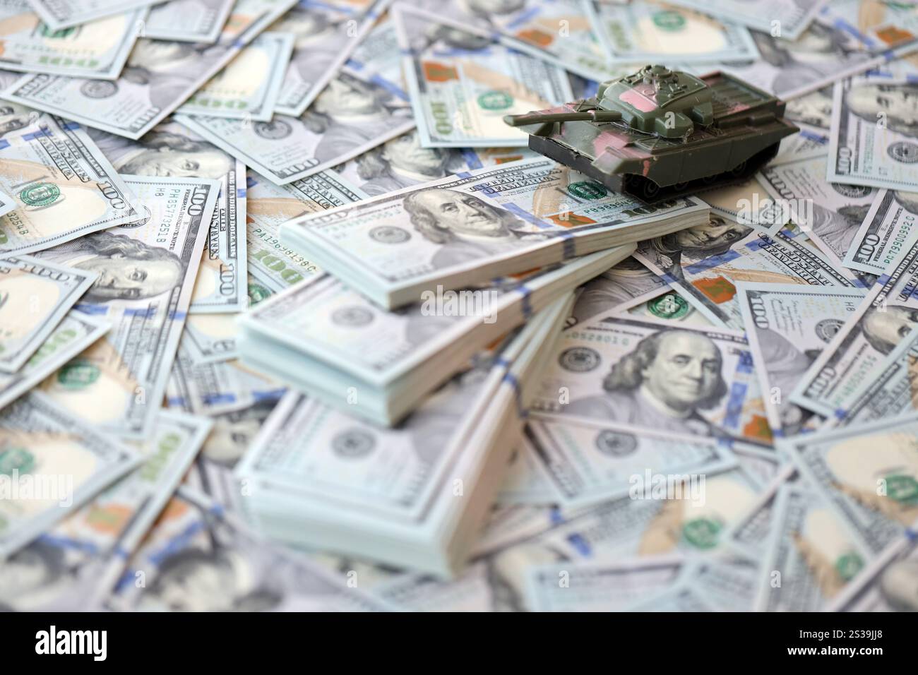 Spielzeugtank auf US-Dollar-Banknoten aus nächster Nähe. Das Konzept der Kriegskosten, der Militärausgaben und der Wirtschaftskrise. Spielzeugtank auf US Hundred Stockfoto