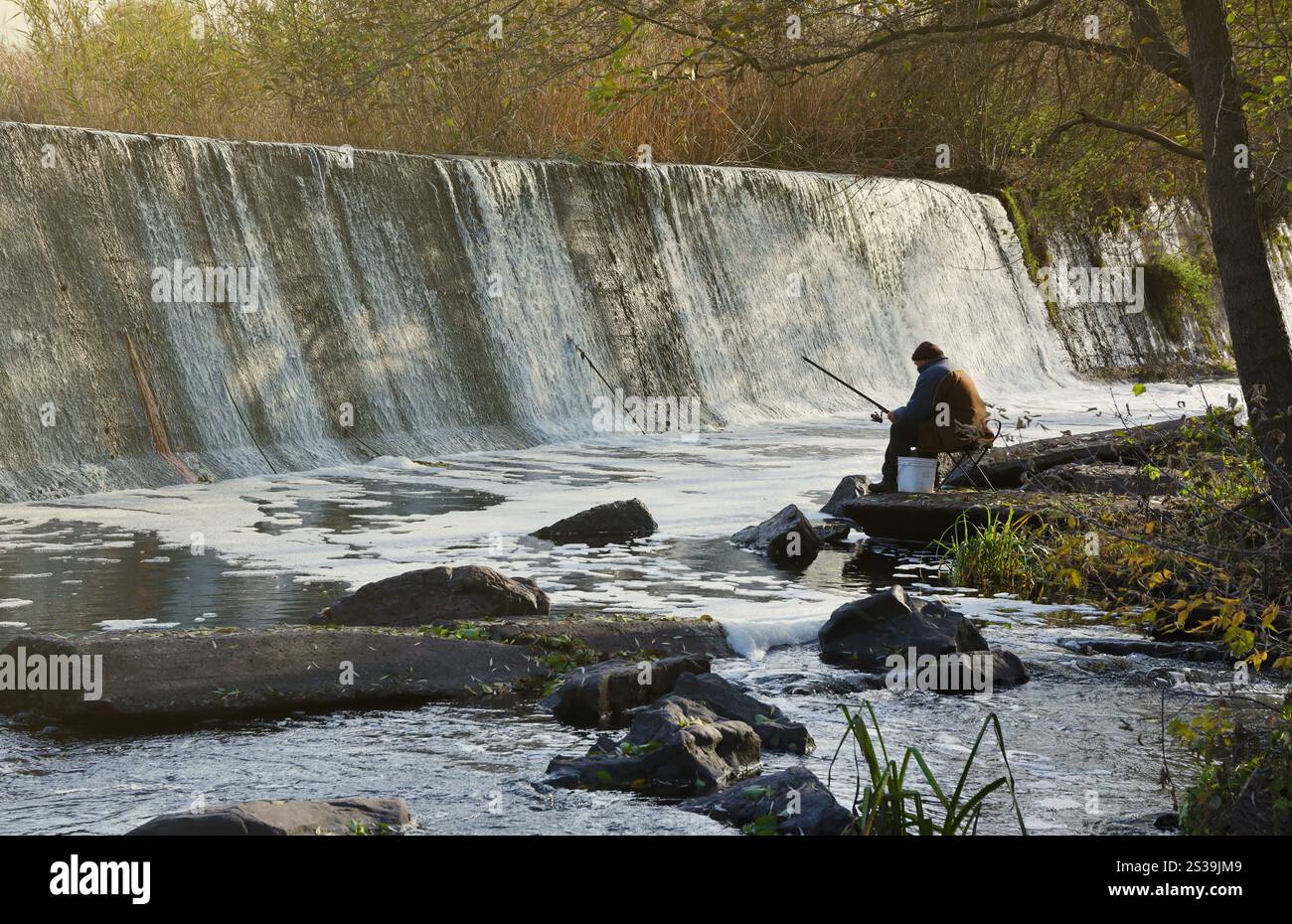Ein stillgelegter Damm, ein künstlicher Wasserfall, der Damm der Butka HPP, befindet sich am Fluss hinter der Brücke über den Hirsky Tikich. Ein Stockfoto