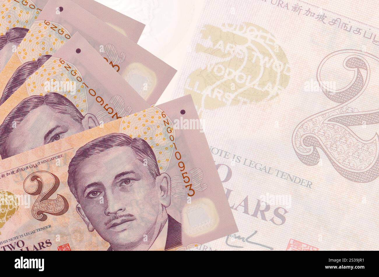 Zwei singapurische Dollarscheine liegen im Stapel auf dem Hintergrund großer halbtransparenter Banknoten. Abstrakter Geschäftshintergrund mit Kopierraum. 2 Singapurisch Stockfoto