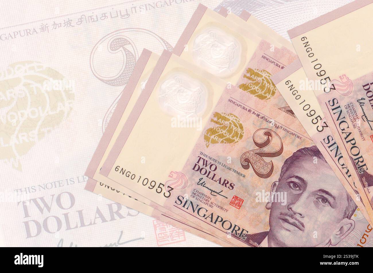 Zwei singapurische Dollarscheine liegen im Stapel auf dem Hintergrund großer halbtransparenter Banknoten. Abstrakte Darstellung der Landeswährung. Unternehmen Stockfoto
