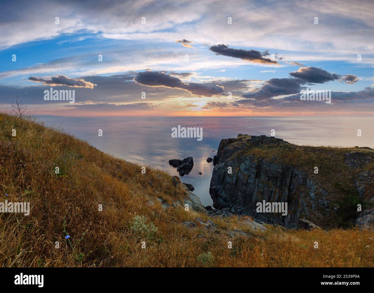 Der Himmel beleuchtet durch steigende Sonne und Seelandschaft von felsigen Klippen. Stockfoto