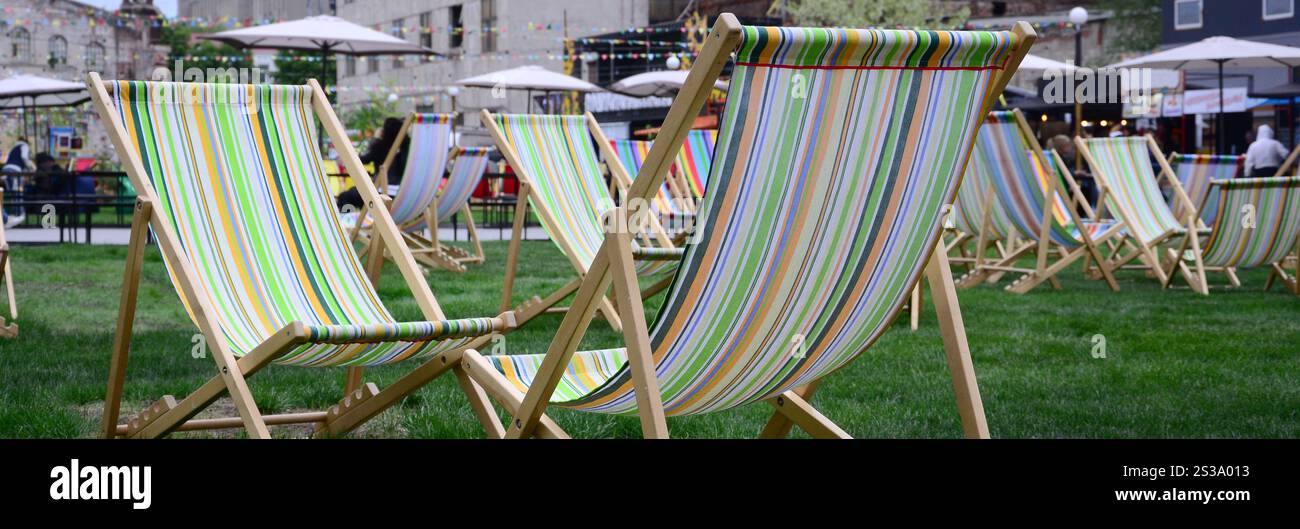 Liegestühle auf einem Rasen. Ruhen Sie sich auf dem Festival aus, im Urlaub. Gartenliegen auf grünem Gras. Gartenbett zum Sonnenbaden und Ausruhen. Sommerstuhl. Chaise Stockfoto