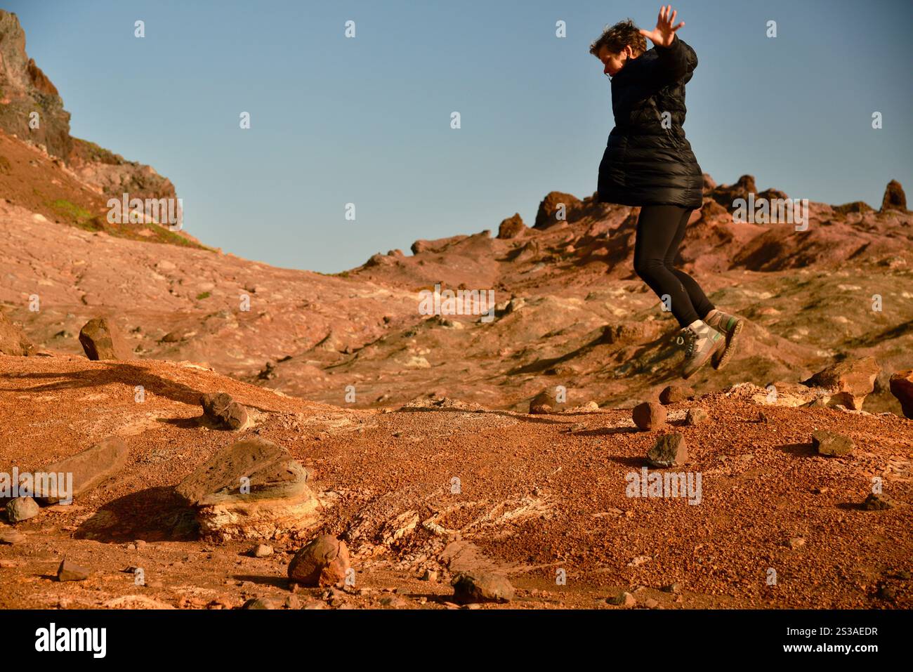 Eine touristische Frau posiert in dem rot gefärbten felsigen Vulkangebiet, ähnlich der rosa Mars-Landschaft auf der Insel Madeira, Portugal. Stockfoto