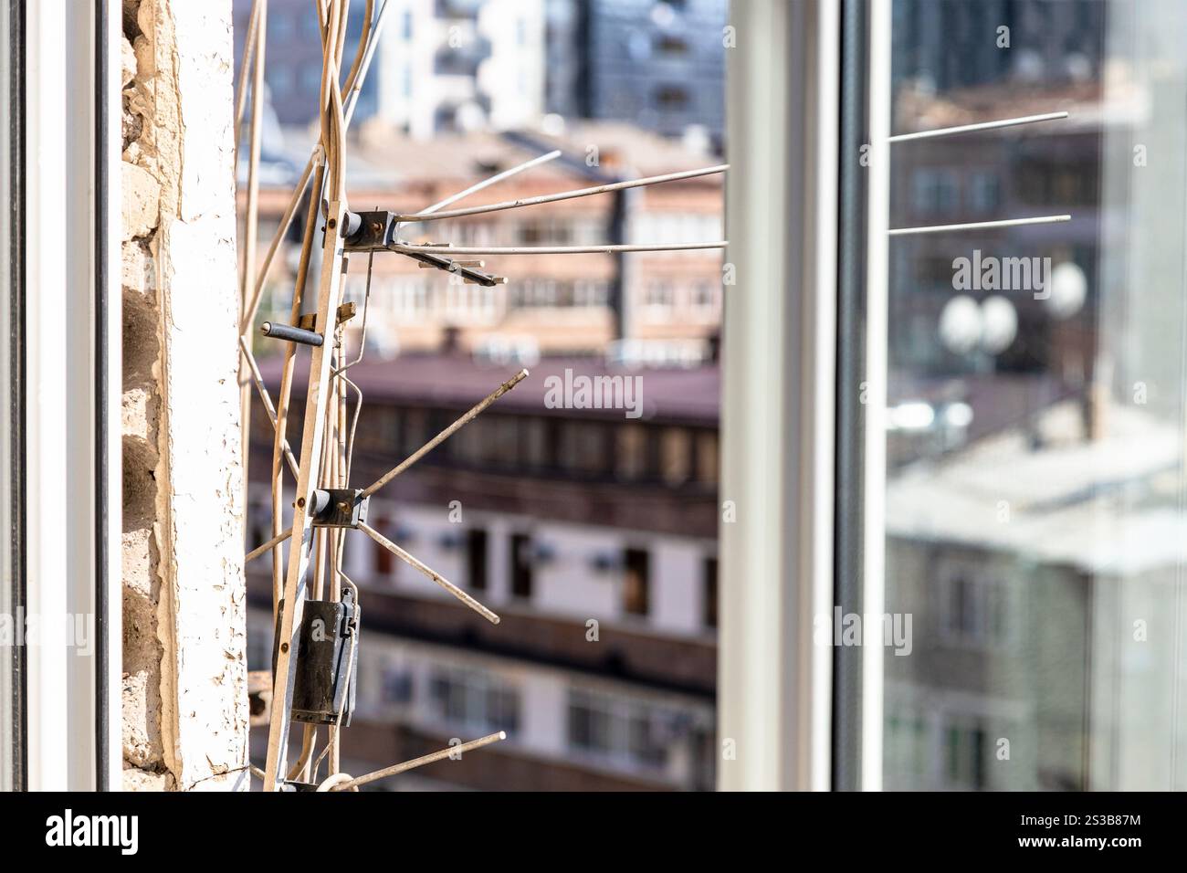 Alte Fernseh- und Radioantennen auf schäbiger Wand des Panels Stadthaus Nahaufnahme und Stadtbild im Hintergrund an sonnigen Sommertagen Stockfoto