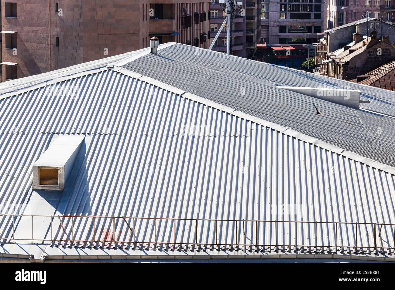 Über dem Dach des Stadthauses, das mit verzinktem Stahldach mit Dachfenster in Jerewan an sonnigen Sommertagen bedeckt ist Stockfoto