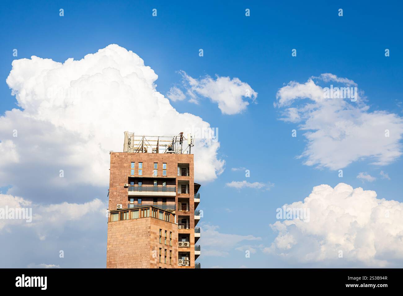 Weiße Wolken am blauen Himmel und Hochhäuser aus Ziegelsteinen in Jerewan, Armenien an sonnigen Sommertagen Stockfoto