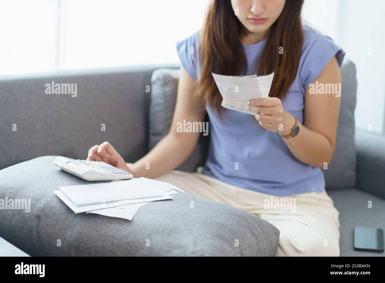 Asiatische Frau, die Papierdokumente hält, berechnet Geldeinsparungen Bezahlen von Rechnungen in mobiler Anwendung mit Smartphone-Zahlung online mit Bezahlen Stockfoto