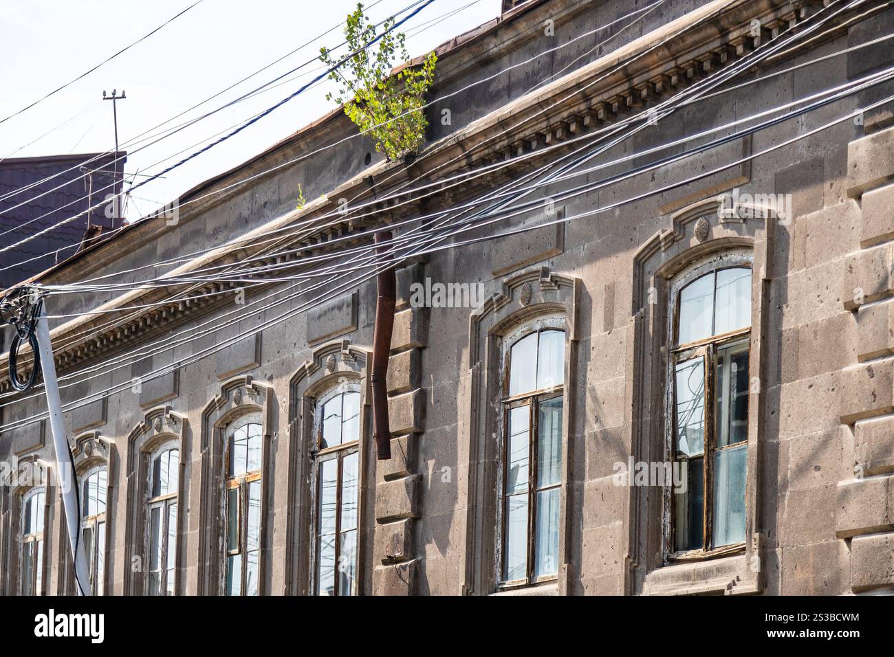 Fassade eines alten Wohnhauses aus schwarzem Tuffstein in Gyumri Stadt, Armenien an sonnigen Sommertagen Stockfoto
