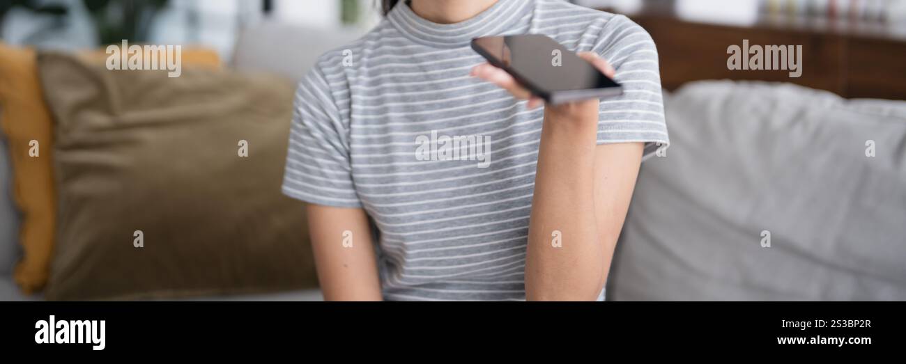 Asiatische Frau mit Sprachassistent auf Smartphone zu Hause Gespräch mit Online-Assistent Sprachchatbot Konversation AI Moderne Technologien Stockfoto