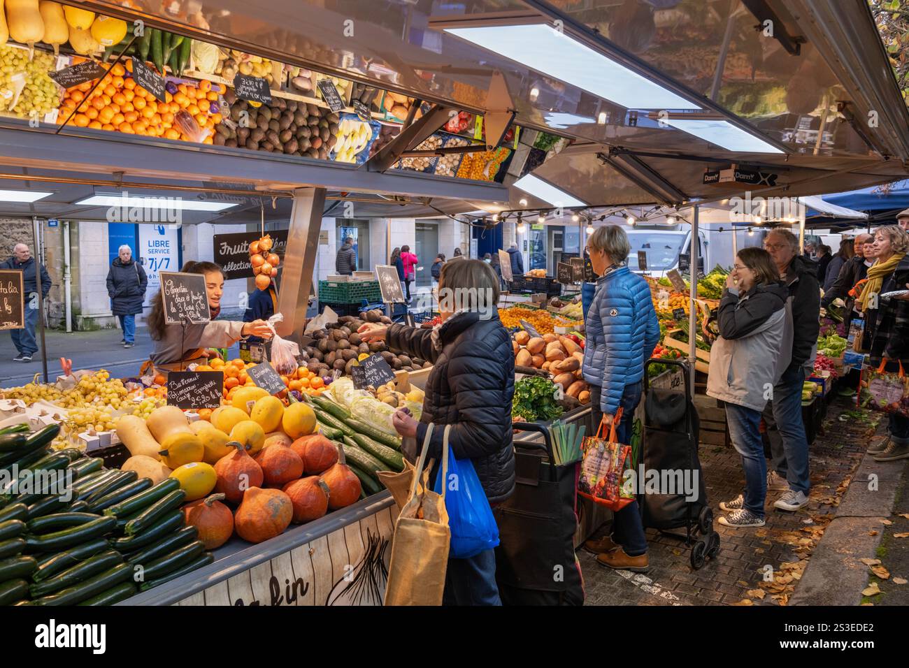 Ein geschäftiger Obst- und Gemüsemarktstand während des traditionellen wöchentlichen Freiluftmarktes am Place Saint Patrice in Bayeux, Département Calvados, Normandie Stockfoto