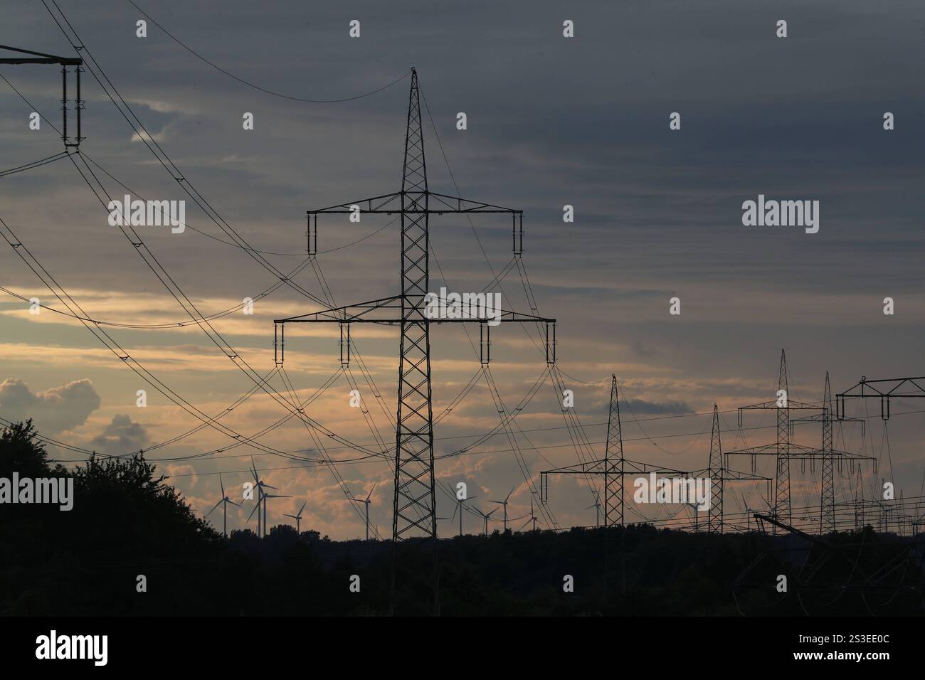 01.07.2024, Greifswald, Mecklenburg-Vorpommern, GER - Silhouetten von Strommasten und Windraedern. Aussen, Aussenaufnahme, Daemmerung, deutsch, Deutschland, Elektrizitaet, Elektrosmog, Energie, Energiebedarf, Energien, Energiepolitik, Energietransport, Energieverbrauch, Energieversorgung, Energiewirtschaft, Europa, europaeisch, Greifswald, Hochspannung, Hochspannungsleitungen, Hochspannungsmasten, Jahreszeit, Kabel, Leitungen, Masten, Mecklenburg-Vorpommern, niemand, QF, Querformat, Schattenrisse, Silhouetten, Strom, Strombedarf, Stromkabel, Stromleitungen, Strommasten, Stromversorgung, Techni Stockfoto