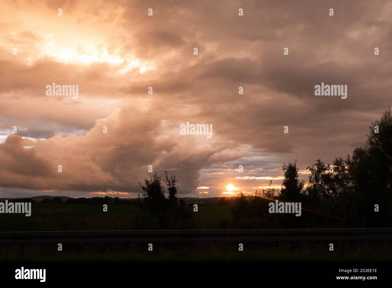 01.07.2024, Greifswald, Mecklenburg-Vorpommern, GER - Dramatischer Wolkenhimmel bei Sonnenuntergang. Abend, Abenddämmerung, Abendhimmel, Abendlicht, Abendroete, Abends, Abendstimmung, Aussen, Aussenaufnahme, Baeume, bewoelkt, Daemmerung, deutsch, Deutschland, dramatisch, einsam, Einsamkeit, Europa, europaeisch, Gegenlicht, Gegenlichtaufnahme, Gewitterwetter, Gewitterwolken, Greifswald, Himmel, Himmelskoerper, Horizont, Idylle, idyllisch, Jahreszeit, Landschaft, Landschaftsaufnahme, Lichtstimmung, Mecklenburg-Vorpommern, Meteorologie, Natur, Naturschauspiel, niemand, QF, Querformat, Ruhe, ruhi Stockfoto
