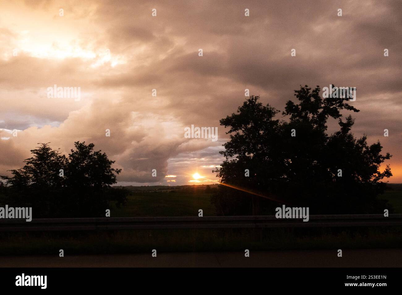 01.07.2024, Greifswald, Mecklenburg-Vorpommern, GER - Dramatischer Wolkenhimmel bei Sonnenuntergang. Abend, Abenddämmerung, Abendhimmel, Abendlicht, Abendroete, Abends, Abendstimmung, Aussen, Aussenaufnahme, Baeume, bewoelkt, Daemmerung, deutsch, Deutschland, dramatisch, einsam, Einsamkeit, Europa, europaeisch, Gegenlicht, Gegenlichtaufnahme, Gewitterwetter, Gewitterwolken, Greifswald, Himmel, Himmelskoerper, Horizont, Idylle, idyllisch, Jahreszeit, Landschaft, Landschaftsaufnahme, Lichtstimmung, Mecklenburg-Vorpommern, Meteorologie, Natur, Naturschauspiel, niemand, QF, Querformat, Ruhe, ruhi Stockfoto