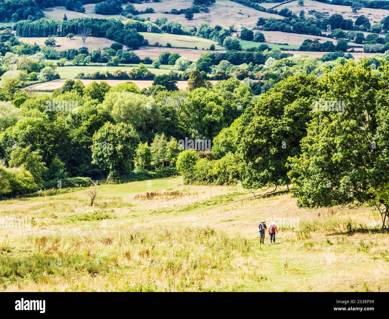 Ein Paar, das einen steilen Hügel in den Cotswolds in der Nähe von Birdlip, Gloucestershire, hinaufreißt. Stockfoto