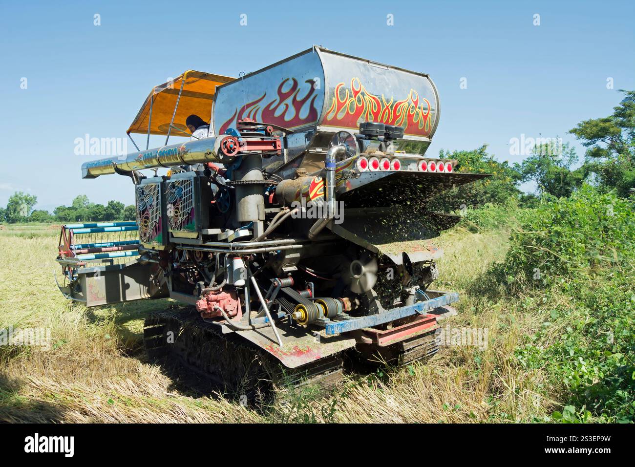 Fahrer an einer farbenfrohen Dreschmaschine arbeitet auf einer kleinen Reisfarm in der Provinz phetchabun im ländlichen thailand Stockfoto