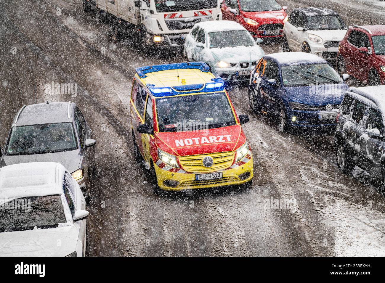 Winterwetter, starker Schneefall, Verkehr im Stadtzentrum, Notarzt, Feuerwehrfahrzeug Essen auf Mission mit Blaulicht blinkend, Nordrhein- Stockfoto