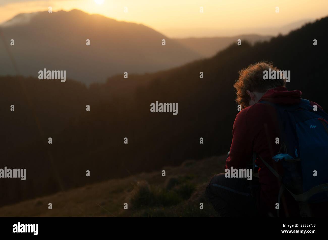 Silhouette eines Fotografen bei Sonnenaufgang in den Bergen, der goldenes Licht und nebelige Schönheit in einer ruhigen und inspirierenden Outdoor-Szene einfängt. Stockfoto
