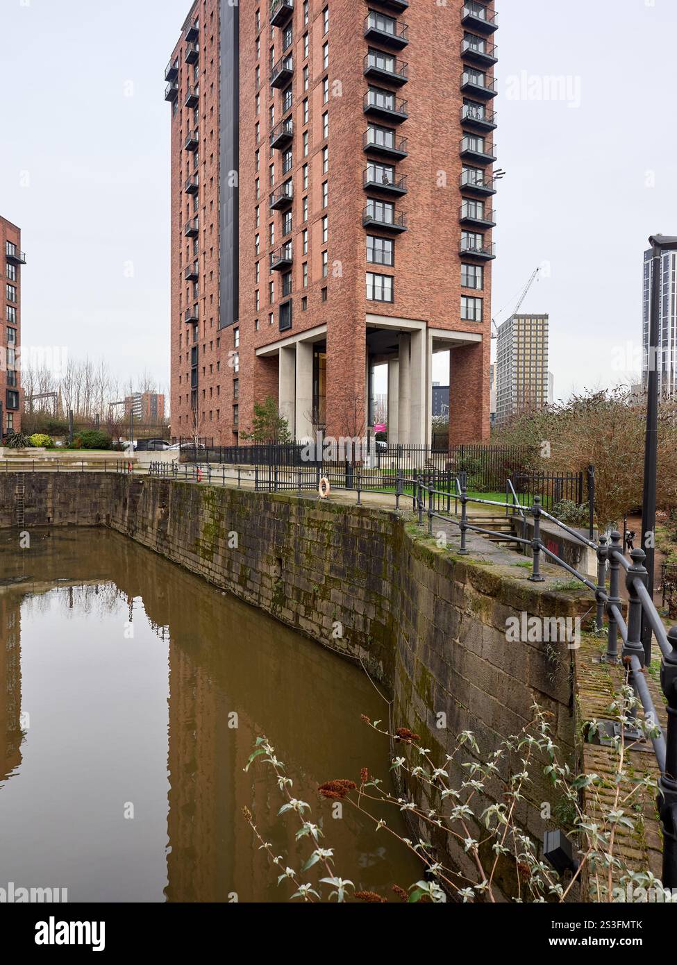 Salford , Manchester, Großbritannien, 01-04-2025: Hohes Wohnhaus aus Backstein, das sich in einer ruhigen städtischen Wasserstraße spiegelt. Stockfoto Salford , Manchester, Großbritannien, 01-04-2025: Hohes Wohnhaus aus Backstein, das sich in einer ruhigen städtischen Wasserstraße spiegelt. Stockfoto