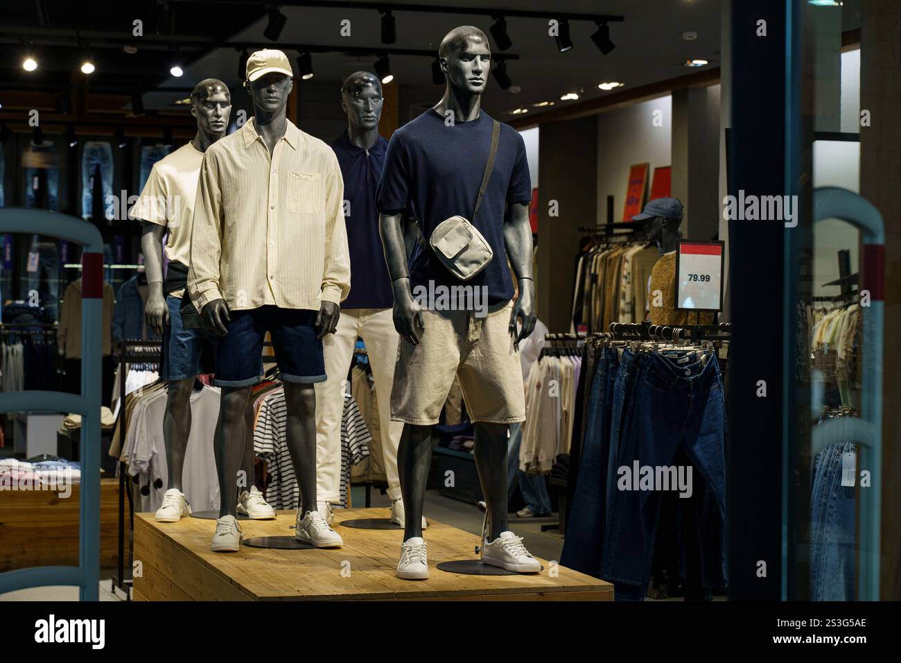 Stilvolle Schaufensterpuppen zeigen moderne Herrenmode in einer pulsierenden urbanen Boutique. Das Arrangement bietet legere Sommerkleidung, die Komfort mit modernem Design verbindet Stockfoto