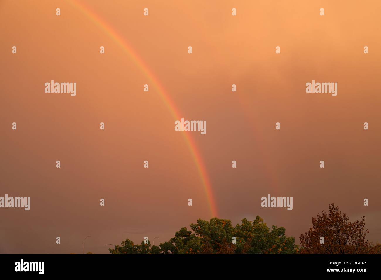 rainbow erscheint in einem rötlich-braunen, rauchigen Himmel Stockfoto