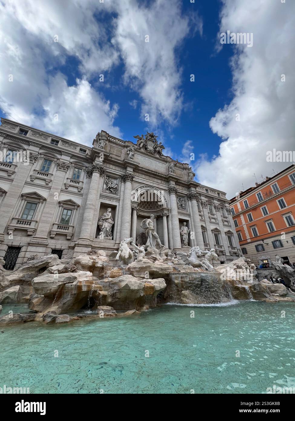 Weitwinkelaufnahme des berühmten Trevi-Brunnens in Rom an einem bewölkten Partytag. Eine beliebte Touristenattraktion mit atemberaubender Architektur. - Smartphone-aufgenommenes Stockfoto