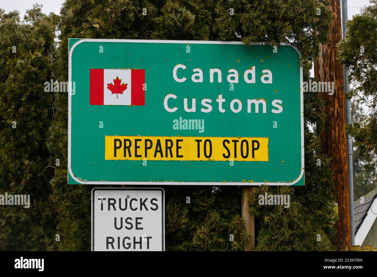 Sumas, WA, USA - 8. Januar 2025; USA Kanada Zollgrenzübergang bereiten sich vor, Straßenschild mit kanadischer Flagge zu stoppen Stockfoto