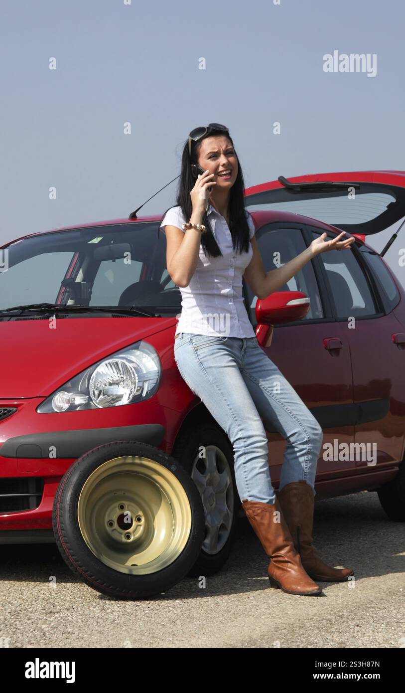 Eine junge Frau mit einem Platten Reifen auf ihrem Auto Stockfoto