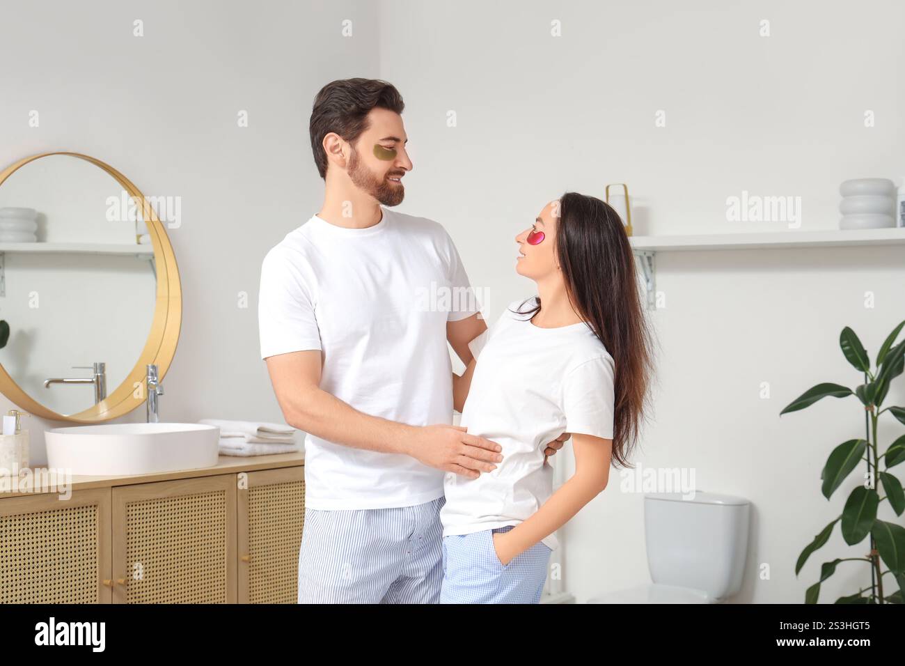Liebevolles Paar mit Flecken unter den Augen, die sich im Badezimmer umarmen Stockfoto