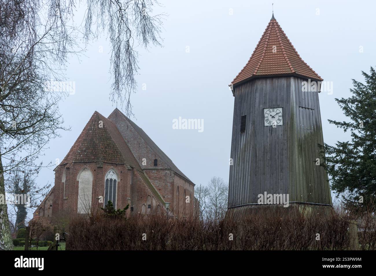 Eine historische Kirche und ihr hölzerner Glockenturm stehen inmitten einer ruhigen Landschaft, die ein zeitloses architektonisches Erbe widerspiegelt. Stockfoto