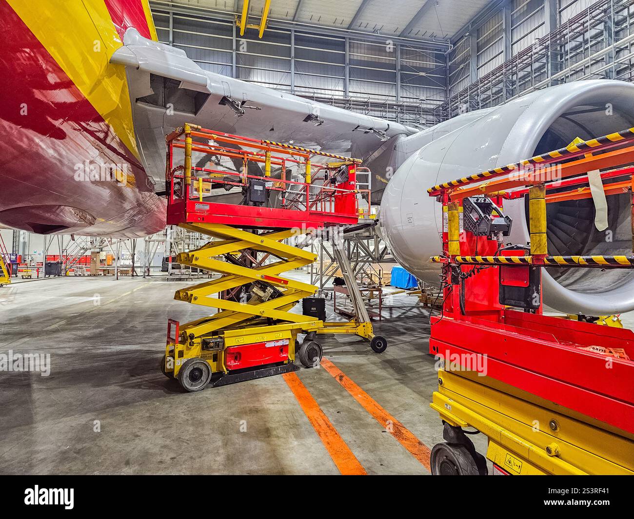 Flugzeugwartung in Hangar mit Scherenaufzügen und Motoren. Hochwertige Fotos Stockfoto