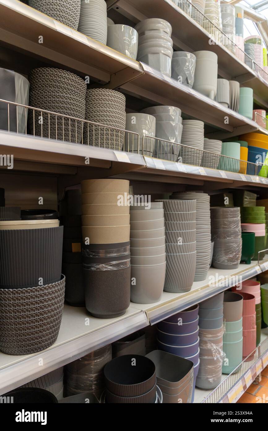 Verschiedene bunte Blumentöpfe aus Keramik und Kunststoff auf dem Regal in einem Pflanzengeschäft. Shopping für trendige Topfblumen und Home-Interior-Design-Konzept. Stockfoto