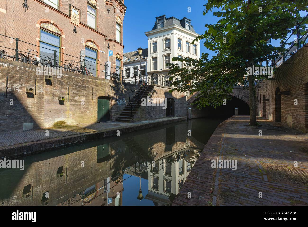 Utrecht, Niederlande. 25. Juni 2024. Canal Utrecht mit einer Treppe zum Kai, auf der anderen Seite ein Baum auf dem Kai. Weitwinkelansicht. Stockfoto