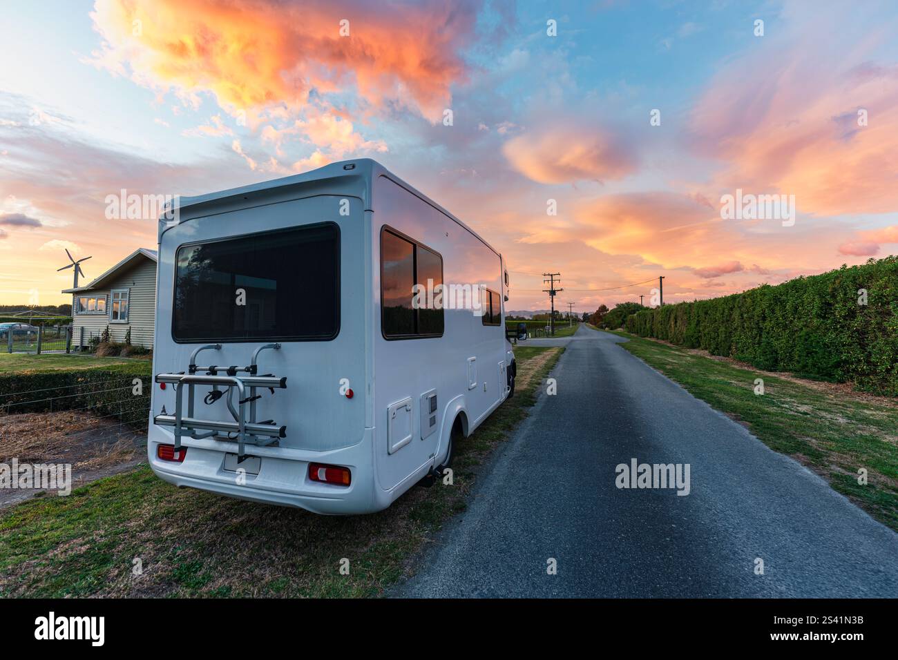 Wohnmobil auf der Straße geparkt mit lebendigem Sonnenaufgangshimmel inmitten von Weinbergen in Neuseeland Stockfoto