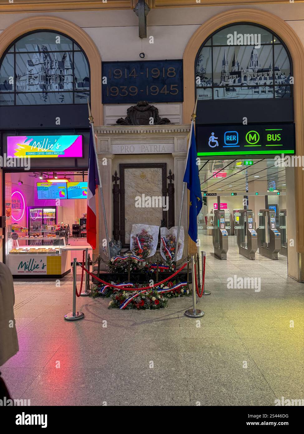 Gedenkstätte für gefallene Soldaten am Bahnhof mit Blumen und Fahnen, die Respekt und Erinnerung in einem öffentlichen Raum zum Ausdruck bringen Stockfoto