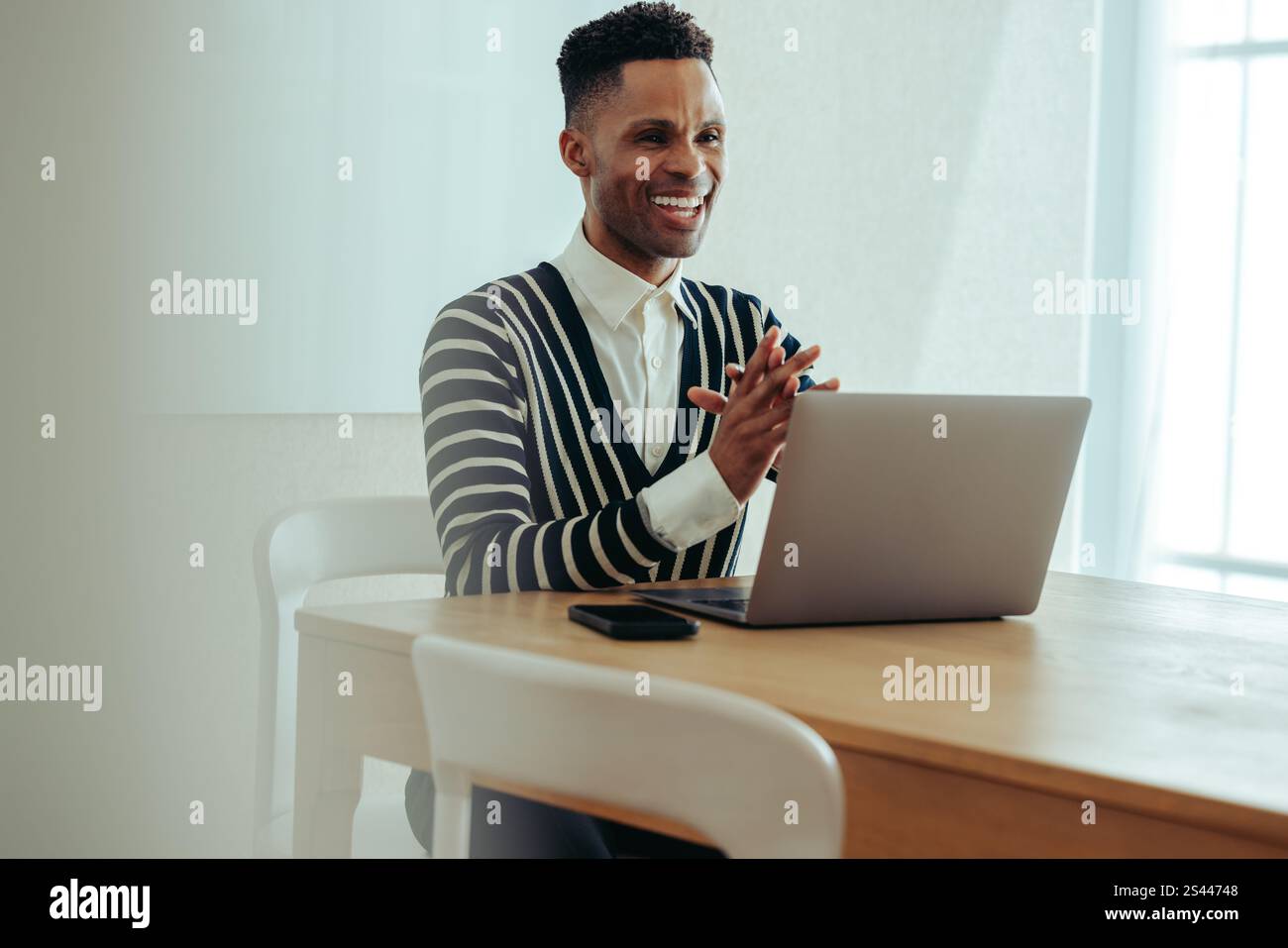 Ein fröhlicher PR-Mitarbeiter, der an einem virtuellen Meeting in einer modernen Büroumgebung teilnimmt. Die Person ist selbstbewusst und konzentriert während der Arbeitsaufnahme Stockfoto