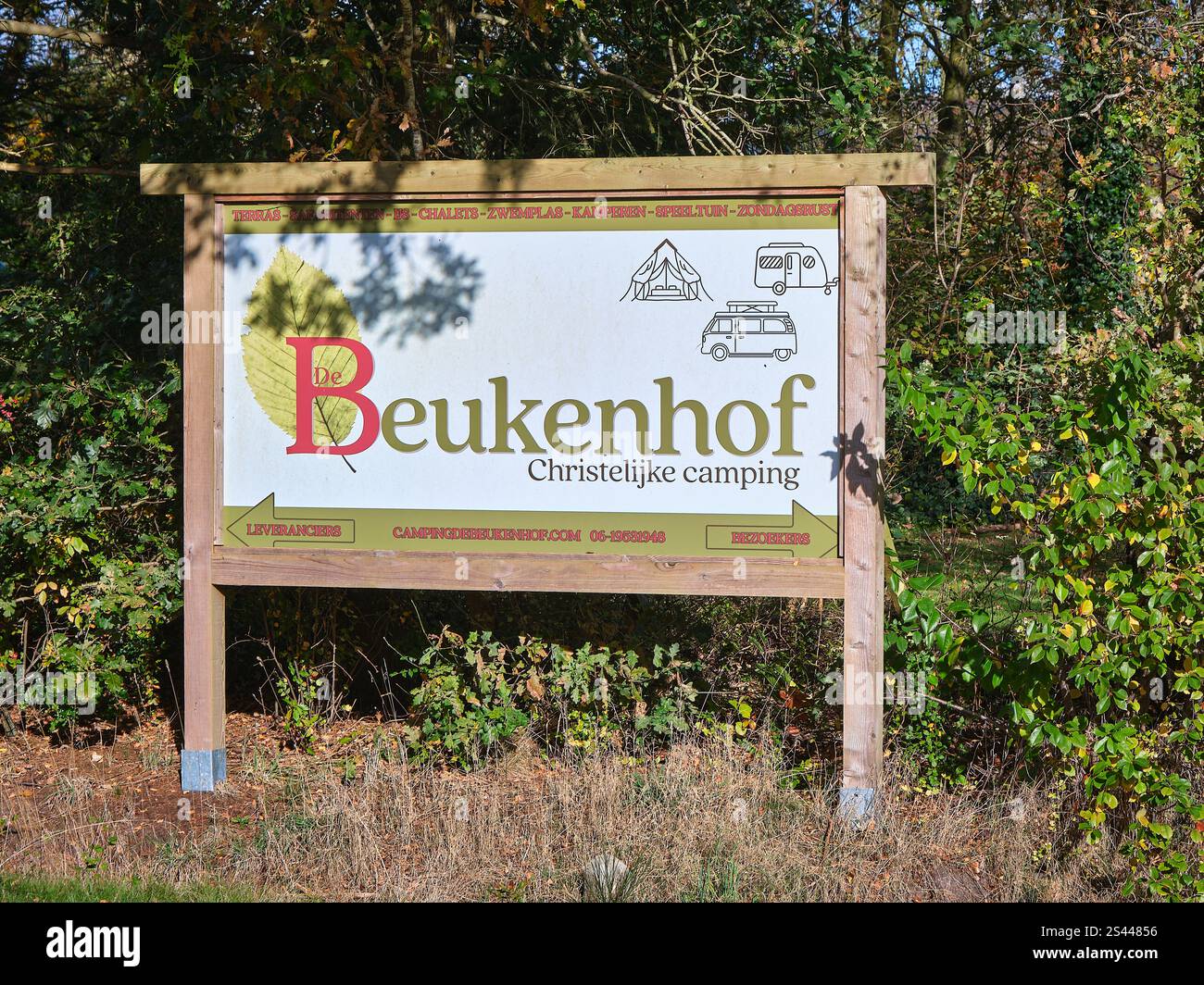 27. Oktober 2024 - Tiendeveen-Niederlande: Ein hölzernes Schild für „de Beukenhof“, ein christlicher Campingplatz, umgeben von Grün an einem sonnigen Tag. Stockfoto