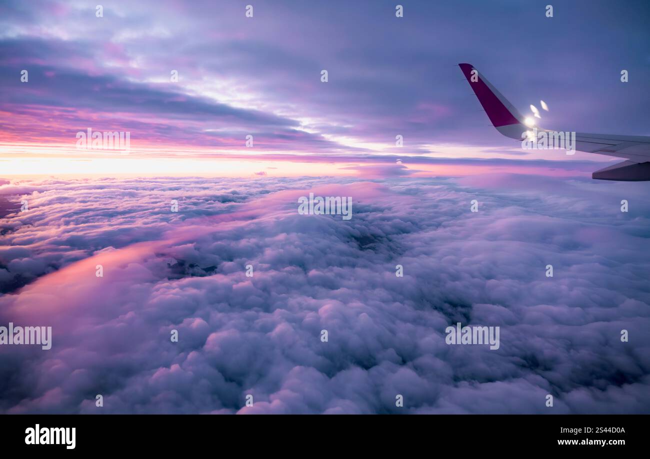 Rosa Wolken durch das Bullauge eines Flugzeugs an einem frühen Wintermorgen. Stockfoto