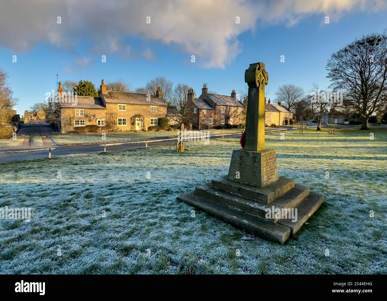 Wintersonnenlicht auf dem Dorfgrün und Kriegsdenkmal im Dorf Langton in North Yorkshire, Großbritannien. Stockfoto Wintersonnenlicht auf dem Dorfgrün und Kriegsdenkmal im Dorf Langton in North Yorkshire, Großbritannien. Stockfoto