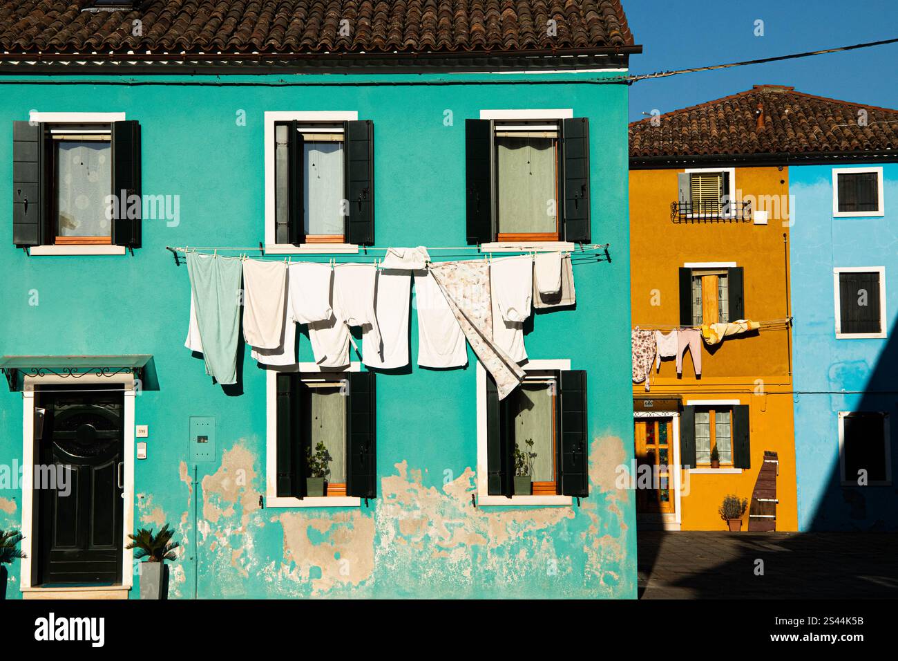 Grüne, gelbe und blaue Lebensräume mit Wäschetrocknung in Murano Stockfoto