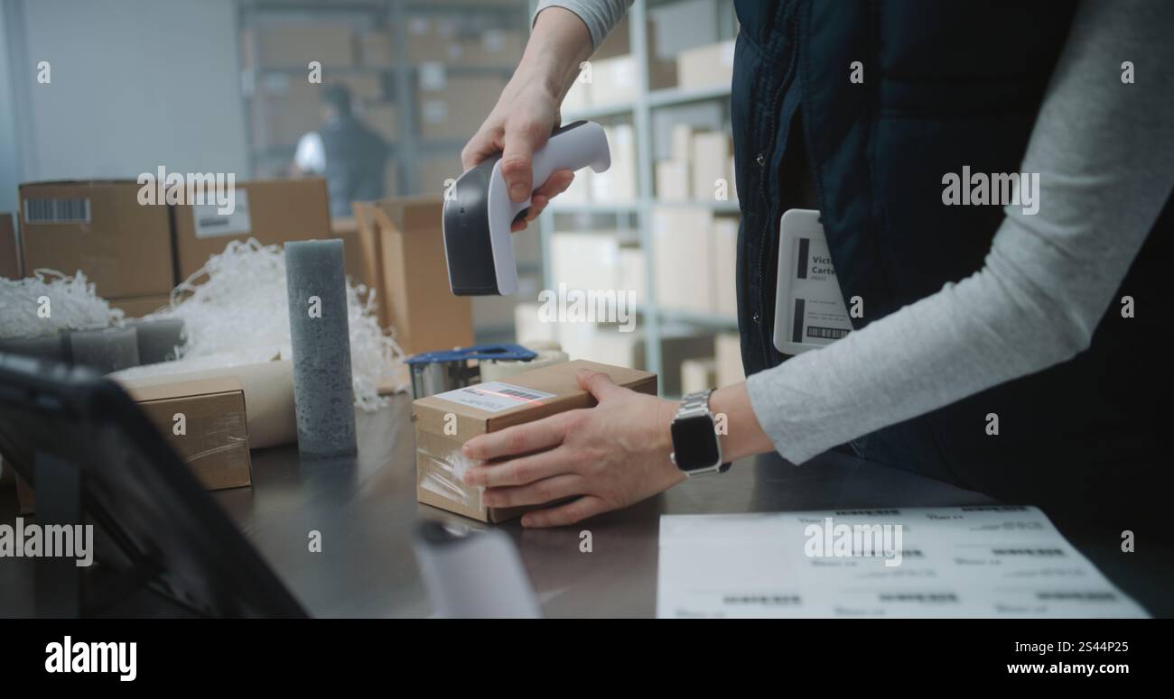 Nahaufnahme der Postangestellten, Versandassistentin, die Kartonpackung mit E-Commerce-Bestellung verpackt, Code scannt, Paket für die Zustellung vorbereitet. Lagereinrichtung, Sortierzentrum des Postdienstes. Stockfoto