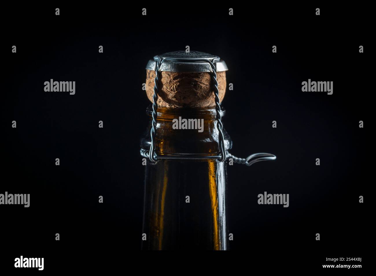 Nahaufnahme eines dunklen Glasflaschenhalses mit Kork und Drahtkäfig auf schwarzem Hintergrund. Bereit für eine festliche Feier. Makrofotografie Stockfoto