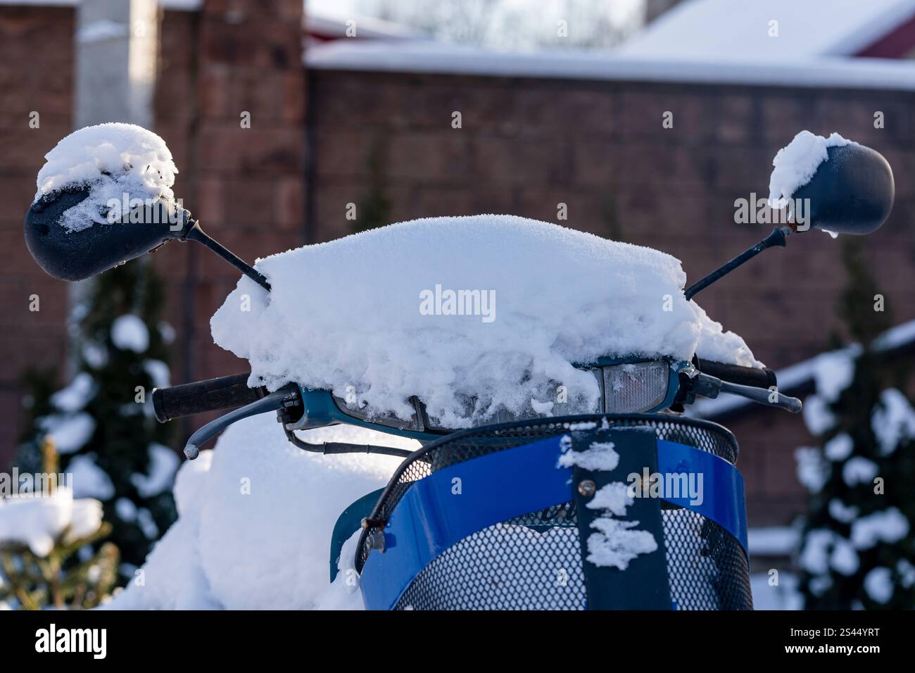 Roller unter Schnee im Hof an einem Wintertag, Nahaufnahme. Teil eines Motorrads, der im Winter mit weißem Schnee bedeckt ist, auf dem Parkplatz, Nahaufnahme Stockfoto